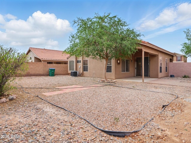 rear view of house with fence, stucco siding, central AC unit, and a patio