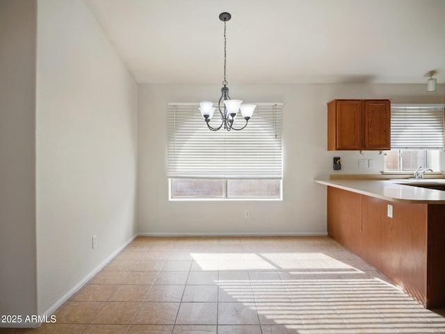 kitchen featuring a chandelier, plenty of natural light, brown cabinets, and light countertops