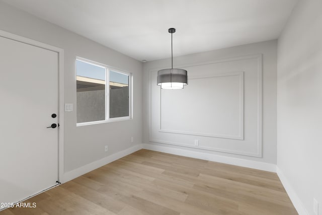 unfurnished dining area featuring light wood-type flooring and baseboards