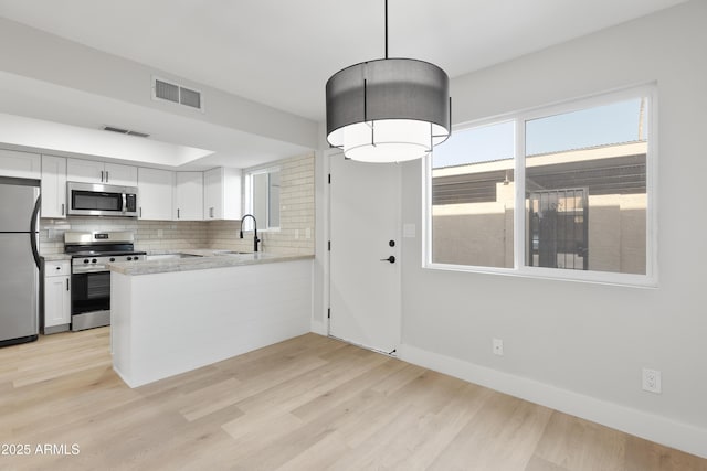 kitchen featuring visible vents, stainless steel appliances, light countertops, and decorative backsplash