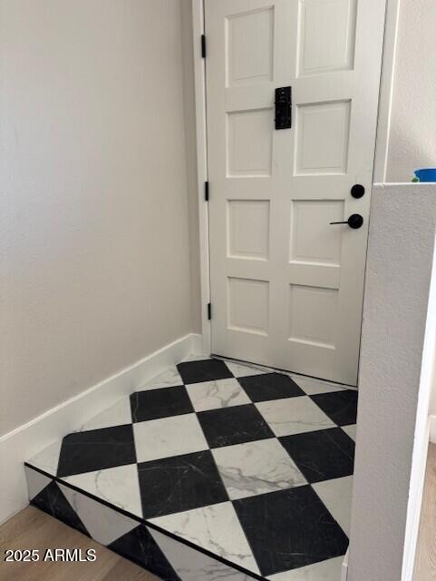 doorway with tile patterned floors and baseboards