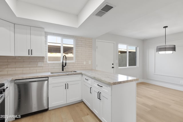 kitchen featuring visible vents, light wood-style flooring, a sink, stainless steel appliances, and a peninsula