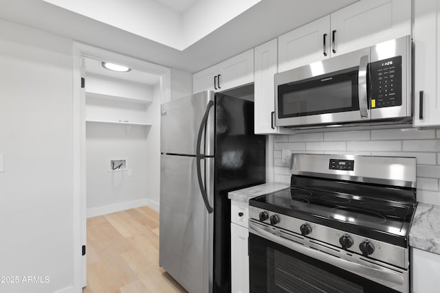 kitchen featuring light stone counters, tasteful backsplash, light wood-style floors, appliances with stainless steel finishes, and white cabinets