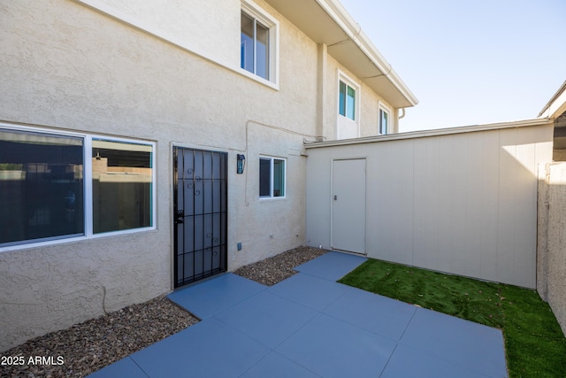 view of exterior entry with a patio and stucco siding