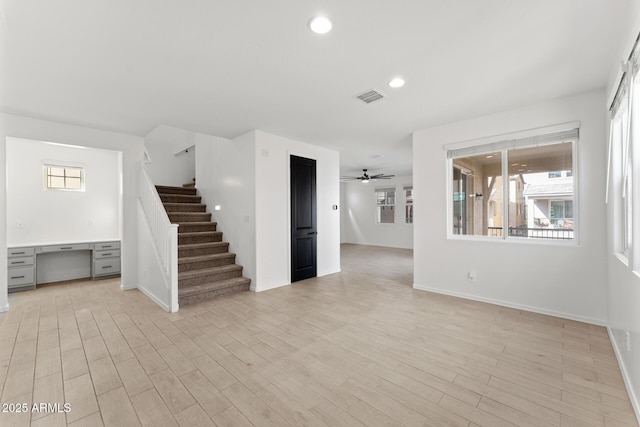 unfurnished living room featuring light hardwood / wood-style flooring, built in desk, and ceiling fan