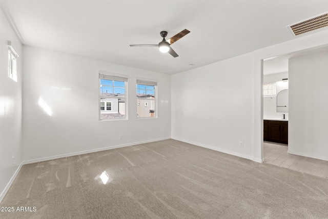 spare room with sink, light carpet, and ceiling fan