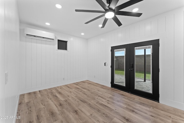 spare room with french doors, ceiling fan, a wall mounted air conditioner, and light hardwood / wood-style floors