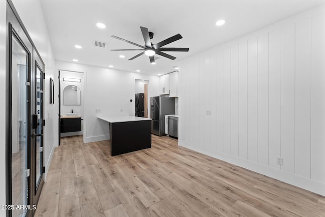 kitchen with ceiling fan, stainless steel appliances, light hardwood / wood-style floors, white cabinets, and a kitchen island