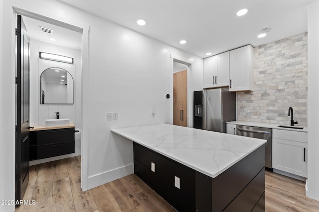 kitchen with white cabinetry, appliances with stainless steel finishes, kitchen peninsula, and sink