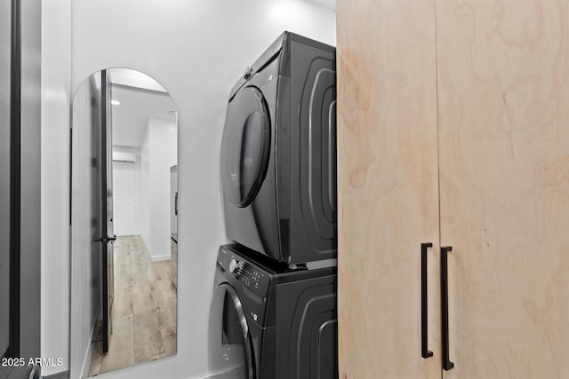 laundry area featuring wood-type flooring and stacked washing maching and dryer