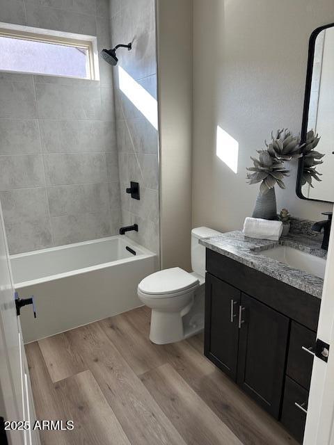 full bathroom with toilet, vanity, wood-type flooring, and tiled shower / bath