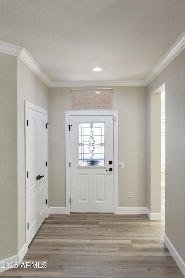 foyer entrance with crown molding and light hardwood / wood-style flooring