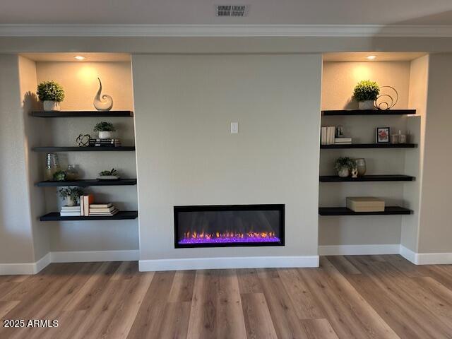 room details with crown molding, built in features, and wood-type flooring