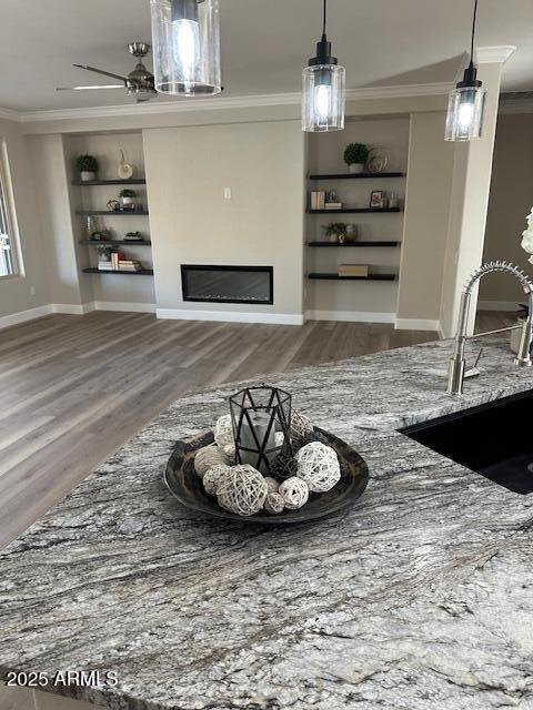 living room with built in features, sink, crown molding, and hardwood / wood-style floors