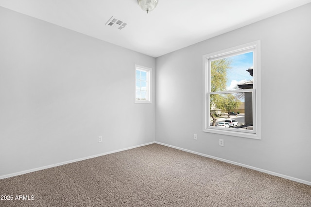 spare room featuring carpet flooring, baseboards, and visible vents