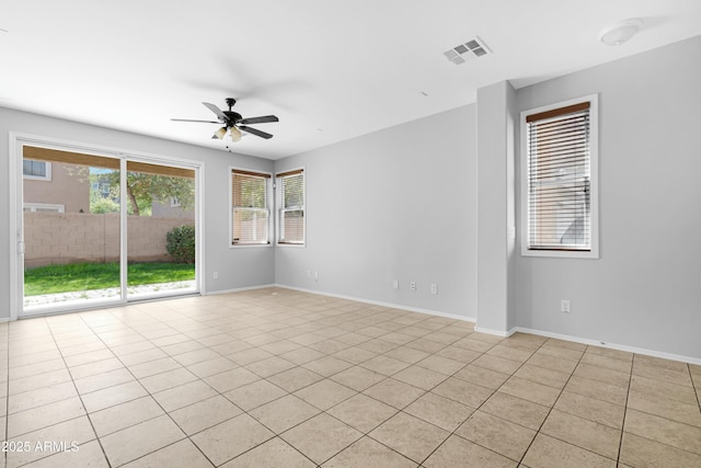 empty room featuring light tile patterned flooring, a ceiling fan, visible vents, and baseboards