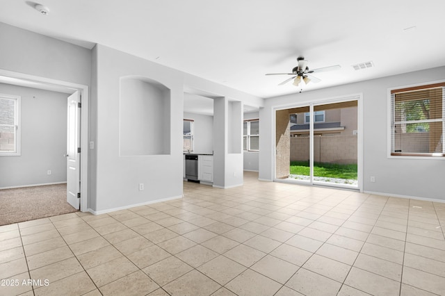 empty room with visible vents, baseboards, a healthy amount of sunlight, and a ceiling fan