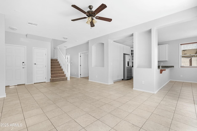 unfurnished living room with stairs, light tile patterned floors, a ceiling fan, and visible vents