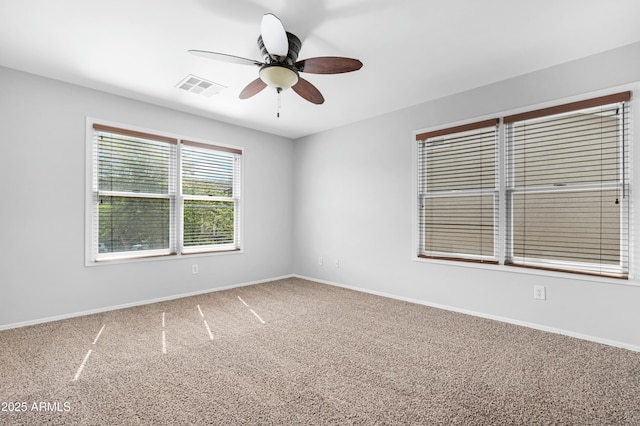 carpeted spare room with visible vents, baseboards, and ceiling fan