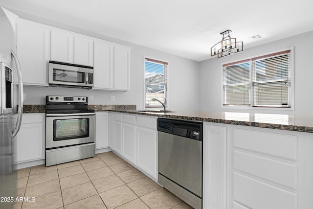 kitchen featuring a sink, white cabinetry, stainless steel appliances, dark stone counters, and light tile patterned flooring