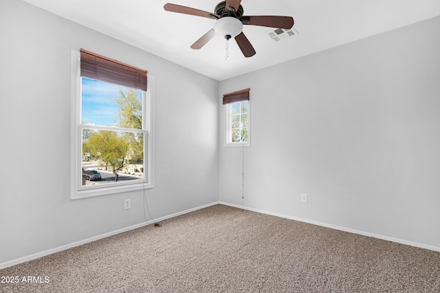 empty room with baseboards, visible vents, carpet floors, and ceiling fan