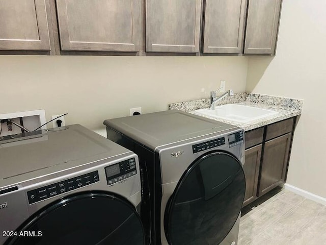 laundry room with light hardwood / wood-style floors, cabinets, separate washer and dryer, and sink