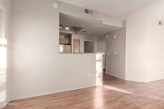 empty room featuring light wood-style flooring, baseboards, and visible vents