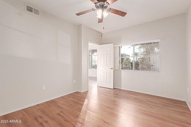 unfurnished room with visible vents, light wood-style flooring, a ceiling fan, and baseboards