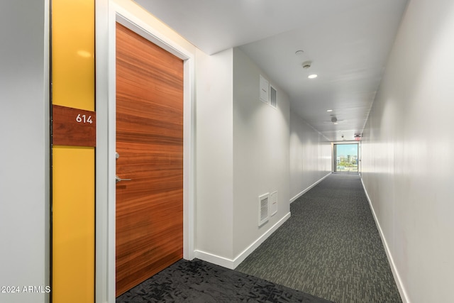 corridor featuring dark colored carpet