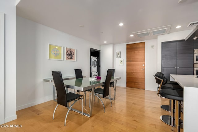 dining room featuring stacked washer and dryer and light hardwood / wood-style flooring