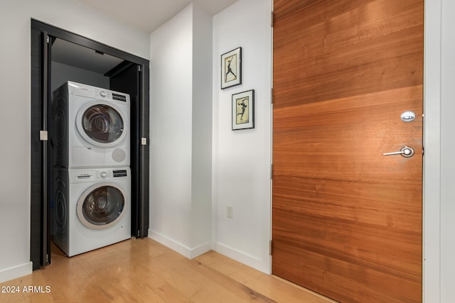 laundry area with stacked washing maching and dryer and light hardwood / wood-style floors