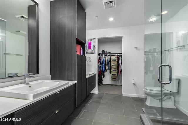 bathroom with a shower with door, vanity, tile patterned flooring, and toilet