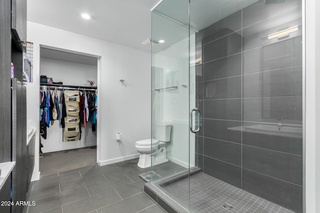 bathroom featuring tile patterned flooring, toilet, and a shower with door