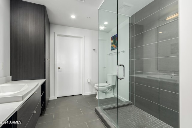 bathroom featuring tile patterned floors, vanity, toilet, and a shower with door