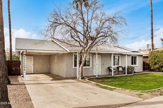 ranch-style house featuring fence, driveway, a front lawn, and stucco siding