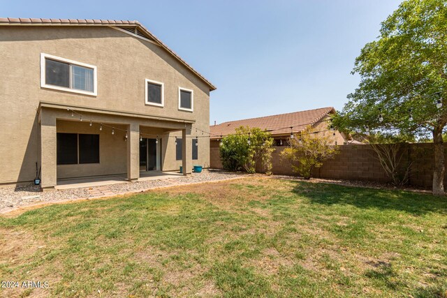 back of property with a yard and a patio