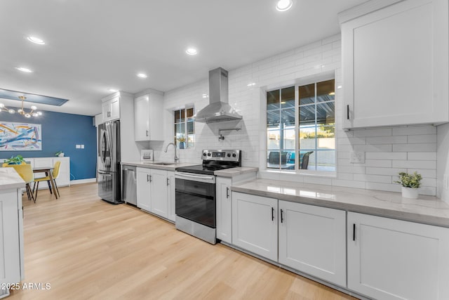 kitchen featuring light hardwood / wood-style flooring, stainless steel appliances, island exhaust hood, decorative backsplash, and white cabinetry