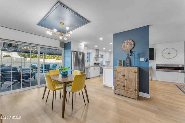 dining space featuring a notable chandelier, light wood-type flooring, sink, and a fireplace