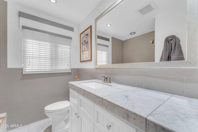 bathroom with tile walls, toilet, and vanity