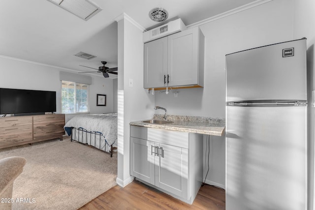 bedroom with crown molding, ceiling fan, stainless steel fridge, sink, and light hardwood / wood-style flooring