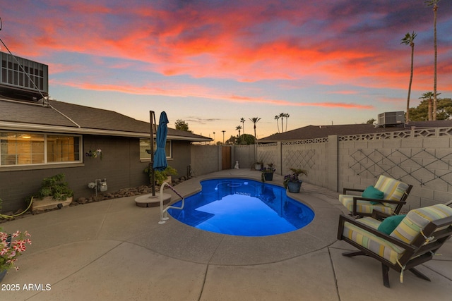 pool at dusk featuring a patio area and cooling unit