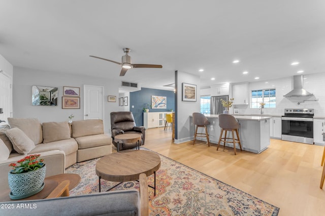 living room featuring ceiling fan, light hardwood / wood-style flooring, and sink