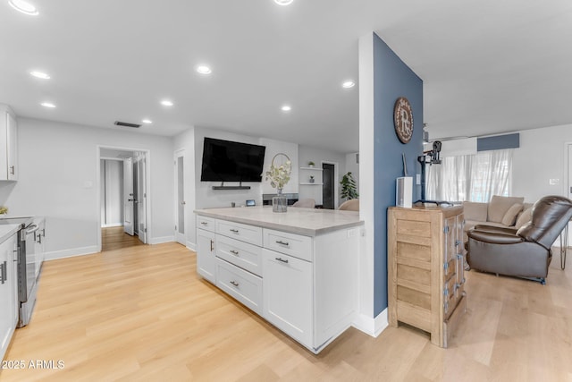 kitchen with white cabinetry, stainless steel electric stove, light wood-type flooring, and light stone countertops