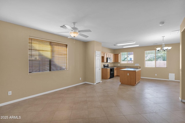 kitchen featuring light tile patterned flooring, ceiling fan with notable chandelier, hanging light fixtures, a kitchen island, and range with electric stovetop