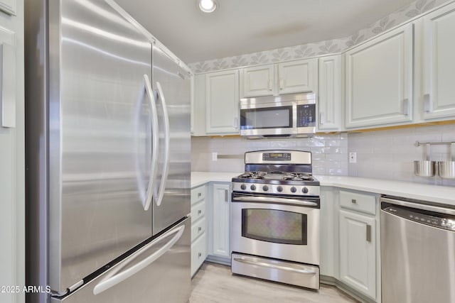 kitchen featuring appliances with stainless steel finishes, light countertops, white cabinetry, and tasteful backsplash