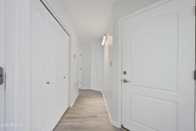 hall with light wood-type flooring and baseboards