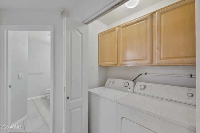 laundry room featuring light tile patterned floors, washing machine and clothes dryer, cabinet space, and baseboards