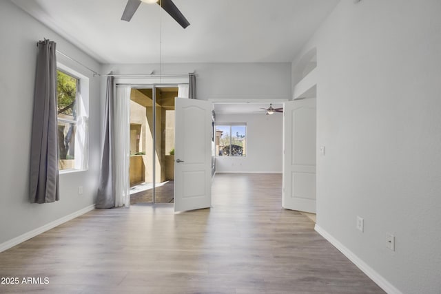 spare room featuring wood finished floors, a ceiling fan, and baseboards