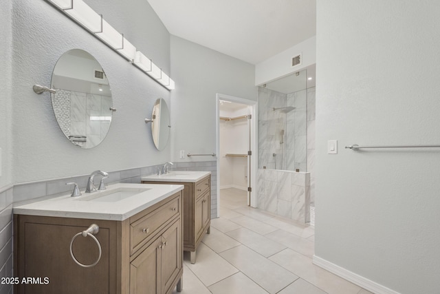 full bathroom featuring two vanities, visible vents, a sink, and tiled shower