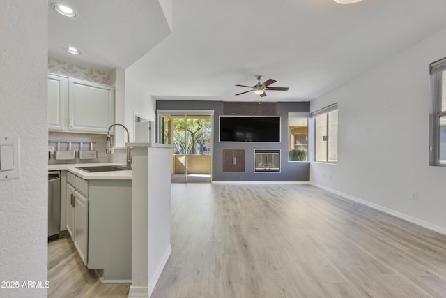 kitchen featuring a wealth of natural light, a glass covered fireplace, light countertops, and a sink